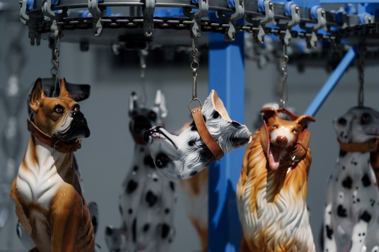 Carrossel suspenso onde estão penduradas, pela trela, várias figuras de cães em cerâmica, sendo que uma delas está partida e apenas está pendurada a cabeça